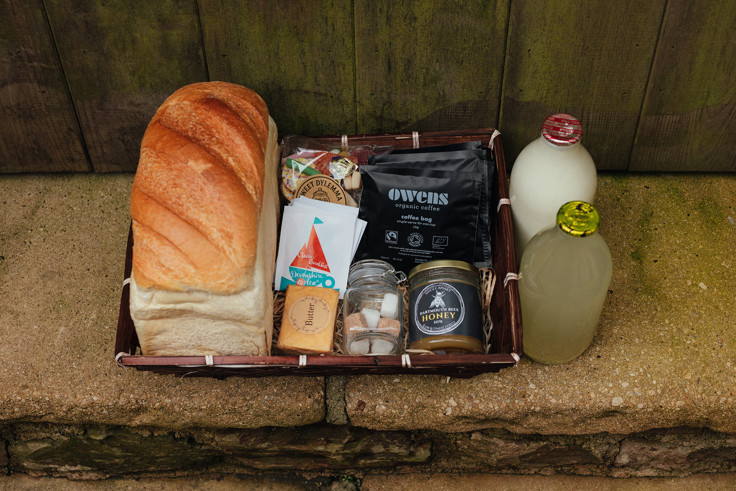 Assorted groceries including bread, honey, and bottles on a stone surface.